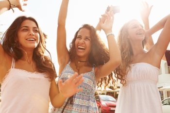 Three Teenage Girls Dancing Outdoors Against Sun