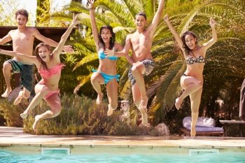 Group Of Teenage Friends Jumping Into Swimming Pool