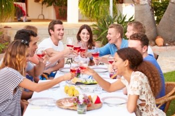 Large Group Of Young Friends Enjoying Outdoor Meal Together