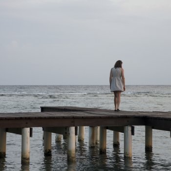 Woman standing on a pier and looking at sea, Utila Island, Bay Islands, Honduras