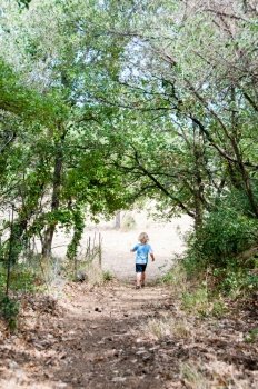 Boy running through woodland path