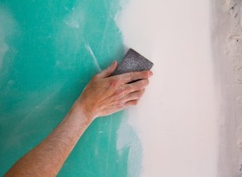 plastering man hand sanding the plaste in drywall seam plasterboard