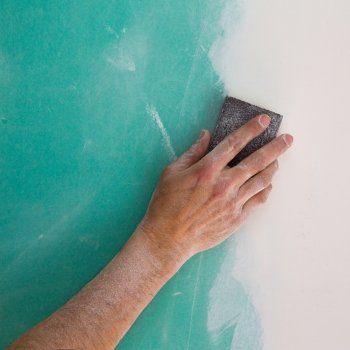 plastering man hand sanding the plaste in drywall seam plasterboard
