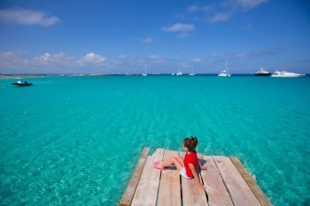 Kid girl looking at tropical Mediterranean sea from wood pier in Formentera Balearic Islands