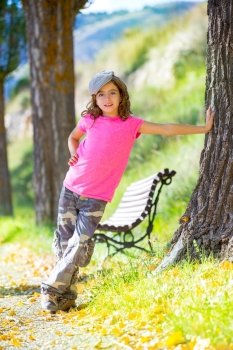 kid girl with camouflage pants and cap in park bench outdoor with pink tshirt