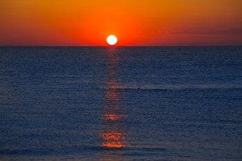 Sunset at Mediterranean sea with orange sky and sun reflection