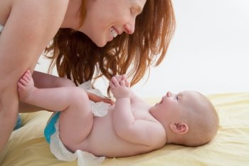 Baby with mother diapering and playing smiling having fun