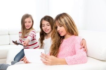 three kid sister friends girls group playing together with tablet pc on white sofa