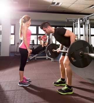 Couple at gym weightlifting workout barbell and dumbbell fitness