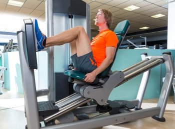 Gym seated leg press machine blond man workout at indoor