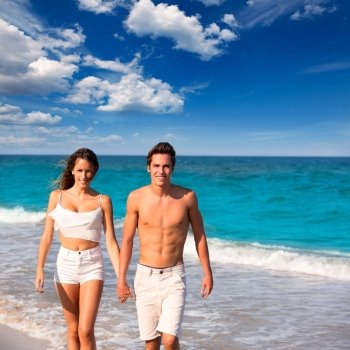 couple young tourists walking in a tropical Mediterranean beach sand