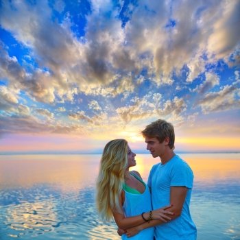 Blond young couple hug in sunset sea lake happy together