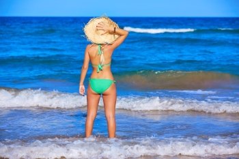 Girl young standing looking at the sea with beach hat rear back view