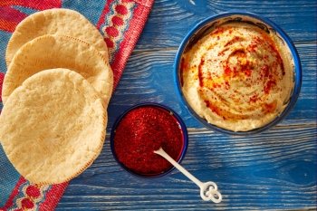 Hummus with pita bread and red pepper powder on blue Mediterranean wood table