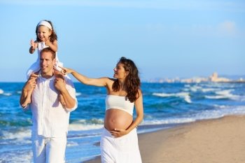 Happy family on the beach sand walking with pregnant mother woman