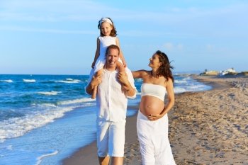 Happy family on the beach sand walking with pregnant mother woman