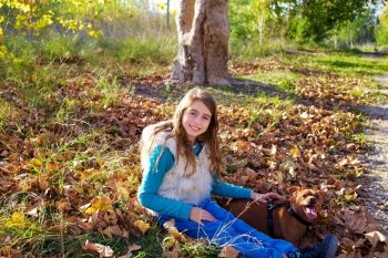 Autumn kid girl with pet dog relaxed in fall forest in Parc de Turia Valencia Spain