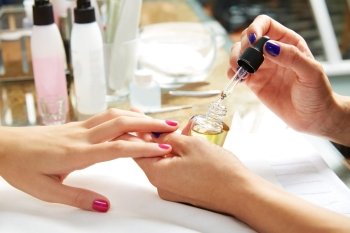 Nails top coat finishing vernis after nail polish in woman hands at salon
