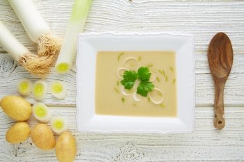 vichyssoise cream soup with leeks and potatoes on white wood table