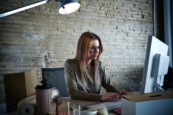 Businesswoman working computer at office with glasses and brickwall background