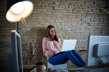 Businesswoman young casual sitting at office working with laptop computer feet on table relaxed