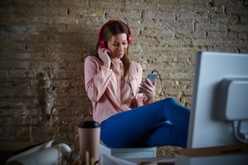 Woman hearing music headphones at office with smartphone relaxed sitting