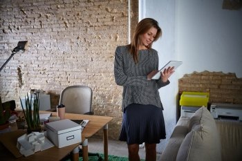 Businesswoman holding tablet pc at office standing and happy