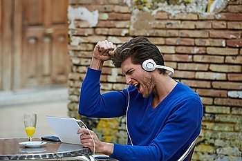 Young man with tablet pc touch listening music outdoor excited expression