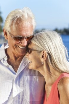 Happy senior man and woman romantic couple laughing together next to tropical sea or river with bright clear blue sky