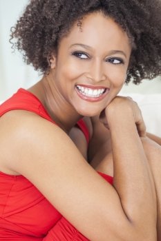 A beautiful mixed race African American girl or young woman wearing a red dress looking happy and smiling with perfect teeth