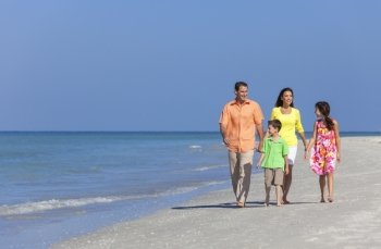 A happy family of mother, father and two children, son and daughter, walking and having fun in the sand of a deserted sunny beach