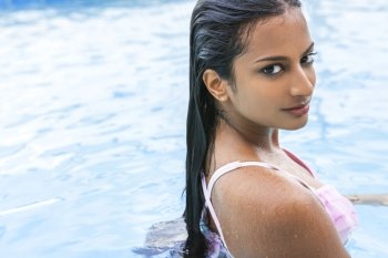 Beautiful sexy young Indian Asian woman or girl wearing bikini in swimming pool