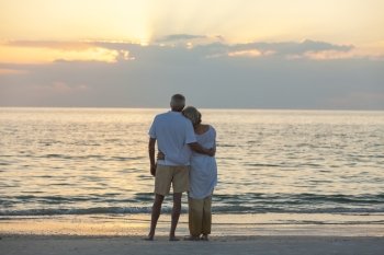 Senior man and woman couple embracing at sunset or sunrise on a deserted tropical beach 