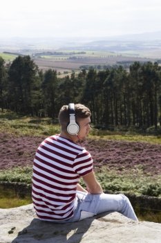 Young Man Listening To Music In Countryside On Headphones