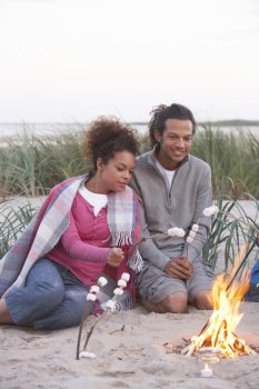 Couple Camping On Beach And Toasting Marshmallows