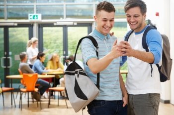 Two Male Students In Classroom Reading Message On Phone