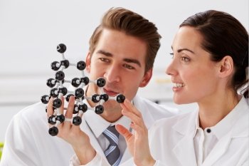 Two Technicians Looking At Molecular Model In Laboratory