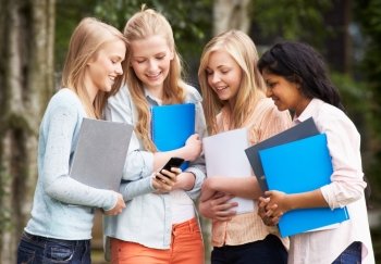 Group Of Female Teenage Students With Mobile Phone Outdoors