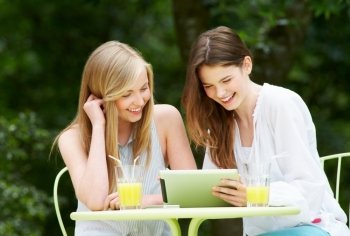 Two Teenage Girls Using Digital Tablet In Outdoor cafe