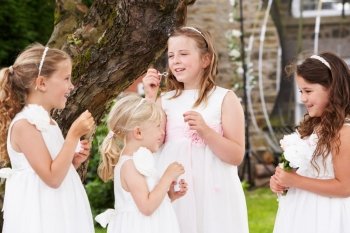 Group Of Bridesmaids Blowing Bubbles In Garden