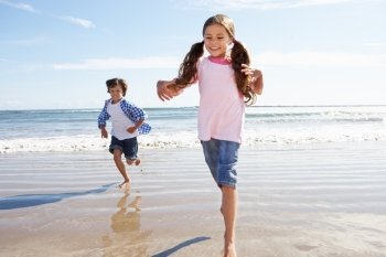 Children Running Away From Breaking Waves On Beach