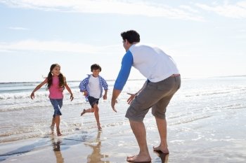 Children Running Towards Father On Beach