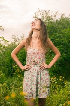 20s female enjoying summertime. Beautiful Young Woman standing in Meadow of Yellow Flowers.