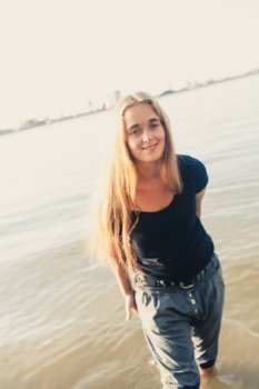 Cute blonde smiling against water of lake.
