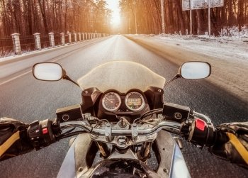 Biker rides on winter slippery road. First-person view.
