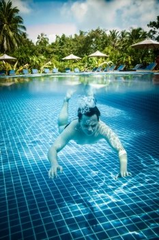 Man dives into a swimming pool views over the water and under water. Maldives.