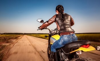 Biker girl in a leather jacket and helmet on a motorcycle