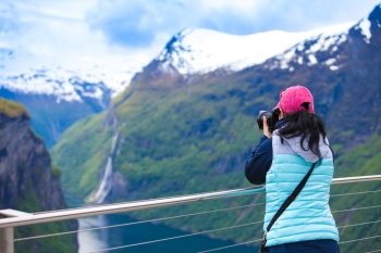 Nature photographer tourist with camera shoots while standing on top of the mountain. Beautiful Nature Norway.