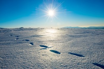 Footprints on the snow. Bright landscape with sun in winter mountains.