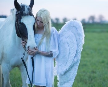 Blond angel looking after the white horse
